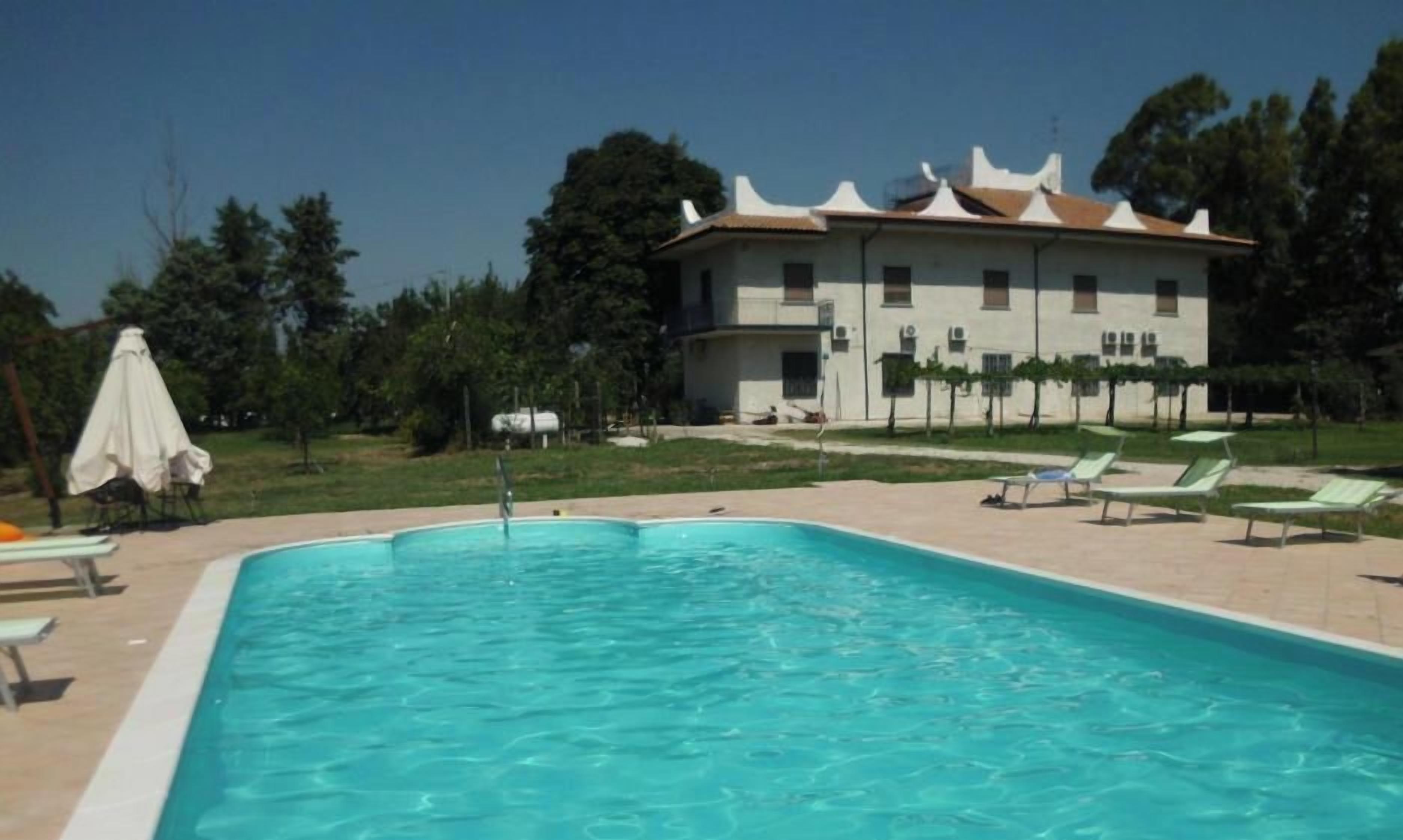 Une piscine avec des chaises longues et un bâtiment en arrière-plan.