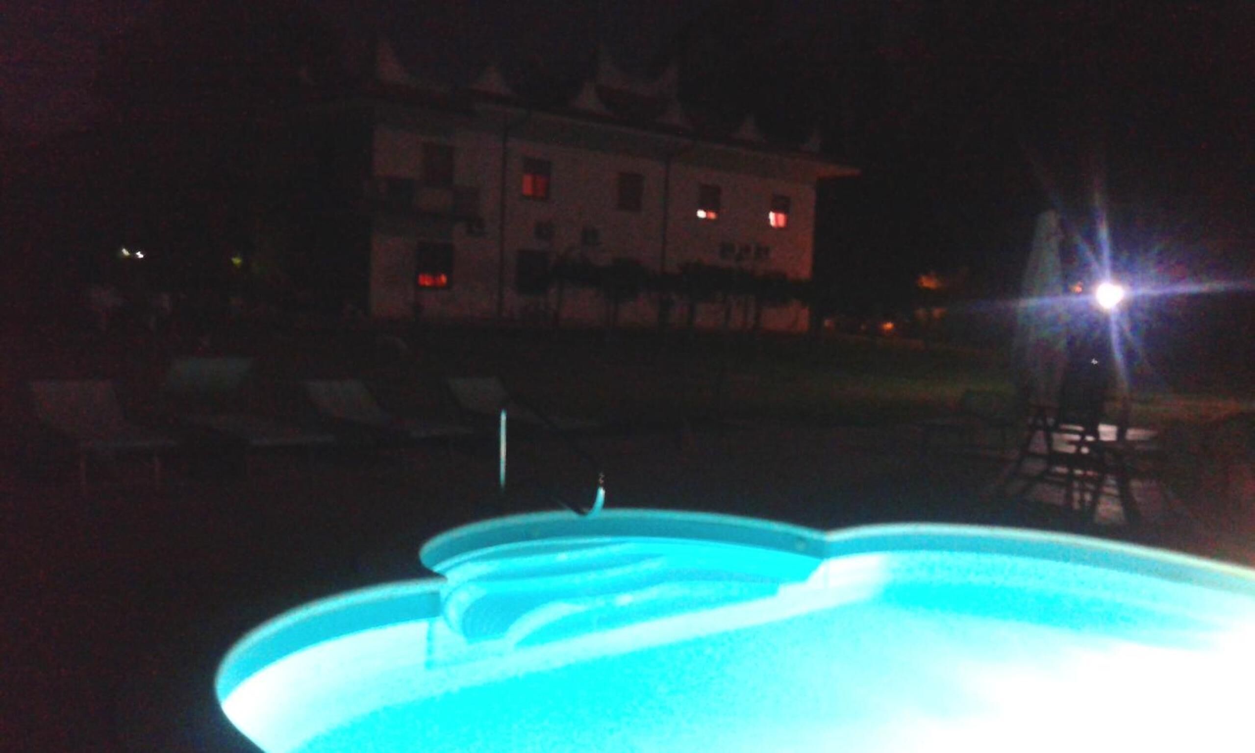 A nighttime view of a swimming pool with a building in the background.