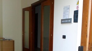 A hallway with a wooden door, a welcome mat, and a wall-mounted sign. - Country House L'Ippocastano (Altavilla Silentina)