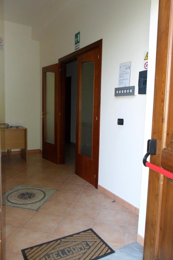 Un pasillo con una puerta de madera, un felpudo y un letrero en la pared.