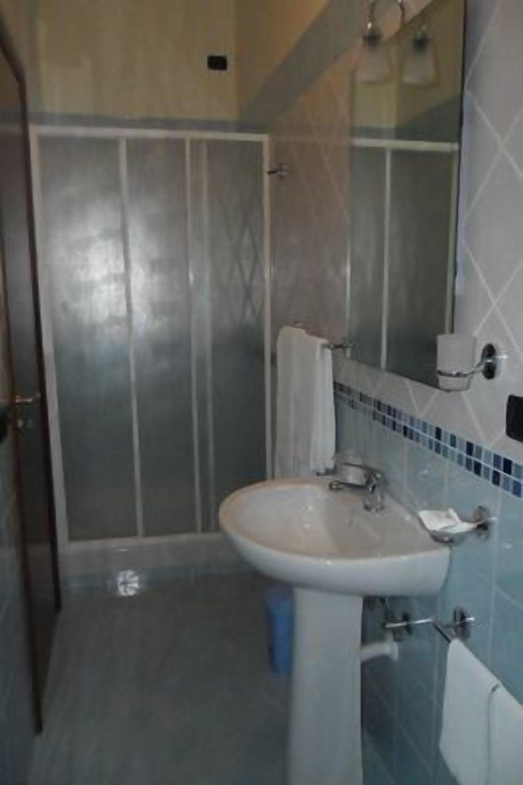 Un baño con lavamanos, espejo y ducha.