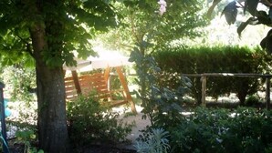 A garden with various potted plants, a wooden swing, and a tree providing shade. - Country House L'Ippocastano (Altavilla Silentina)