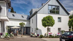 A modern building with a sloped roof, large windows, and a paved entrance area with a scooter and bicycles parked outside. - Villa Verde (Salzburg)