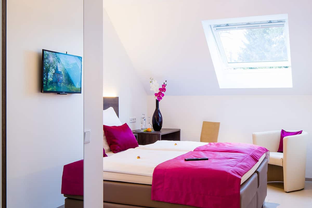 A modern bedroom with a bed, a desk, a chair, and a window.