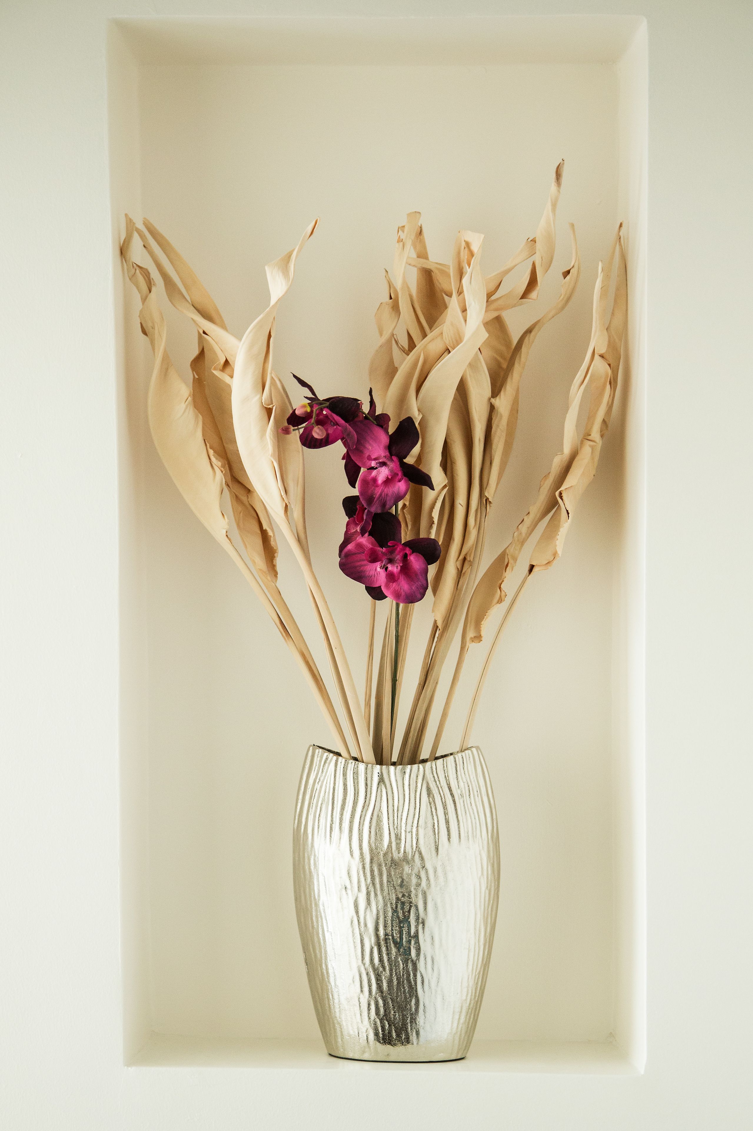 Um vaso com flores secas e algumas flores frescas.