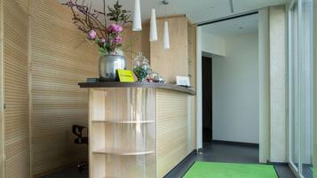 Un mostrador de recepción con alfombra verde, paneles de madera y un jarrón de flores.