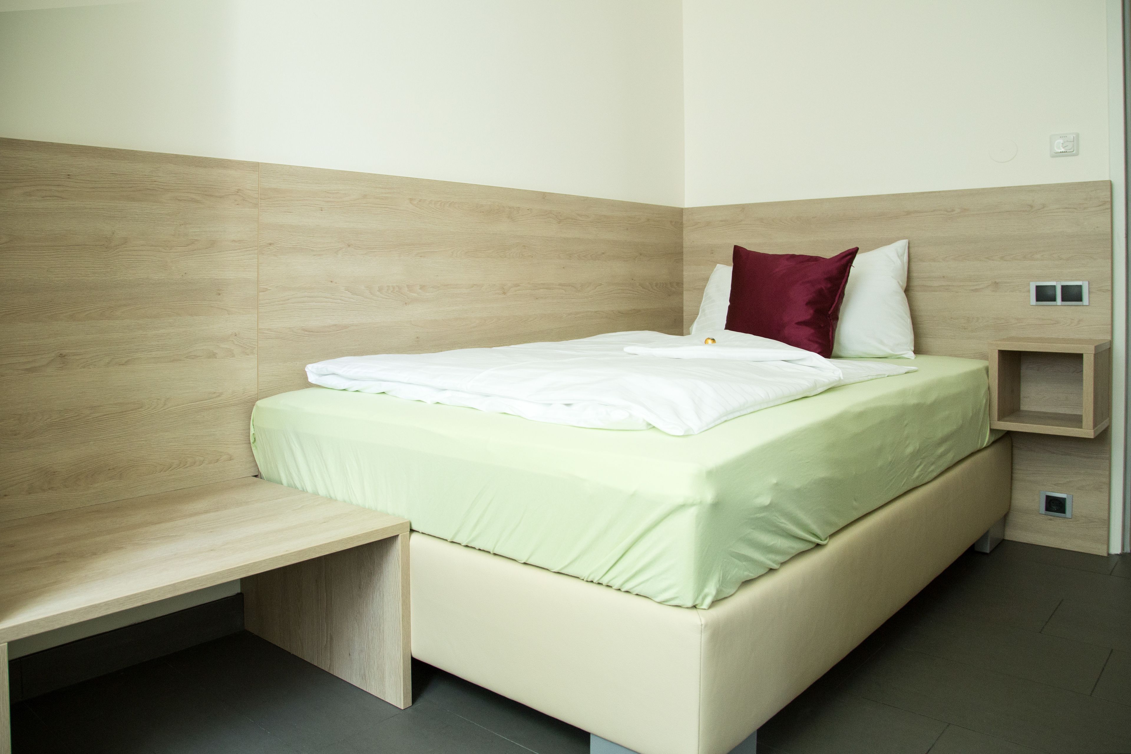 Een moderne slaapkamer met een bed, een bankje en een nachtkastje.