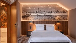 A hotel room with a large bed, wooden headboard, and a cityscape mural on the wall. - Artis Hotel & Spa (Zamosc)