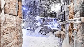 A snow-covered outdoor area with a stone wall and a metal gate.