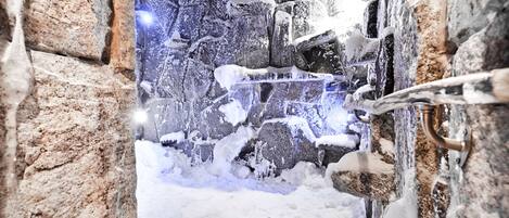 A snow-covered outdoor area with a stone wall and a metal gate.