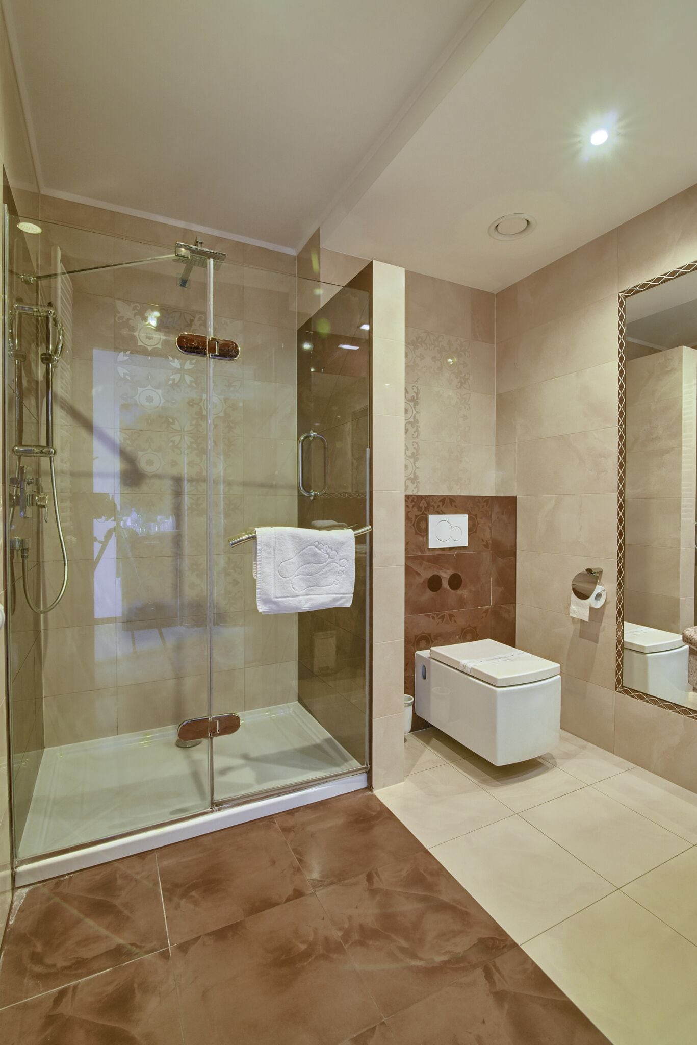 Une salle de bain moderne avec une douche à parois de verre, des toilettes blanches et un grand miroir.