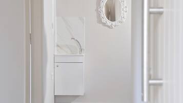 Un baño con lavamanos de mármol, un mueble pequeño y un espejo decorativo.