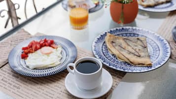 A breakfast table with plates of food, a cup of coffee, and a glass of orange juice.