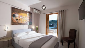 Una camera d'albergo moderna con un letto grande, una sedia, un quadro e vista sull'esterno.