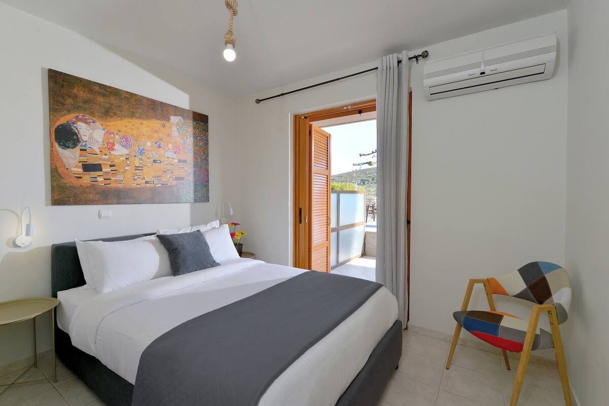 Un dormitorio con cama, un cuadro, aire acondicionado y una silla.