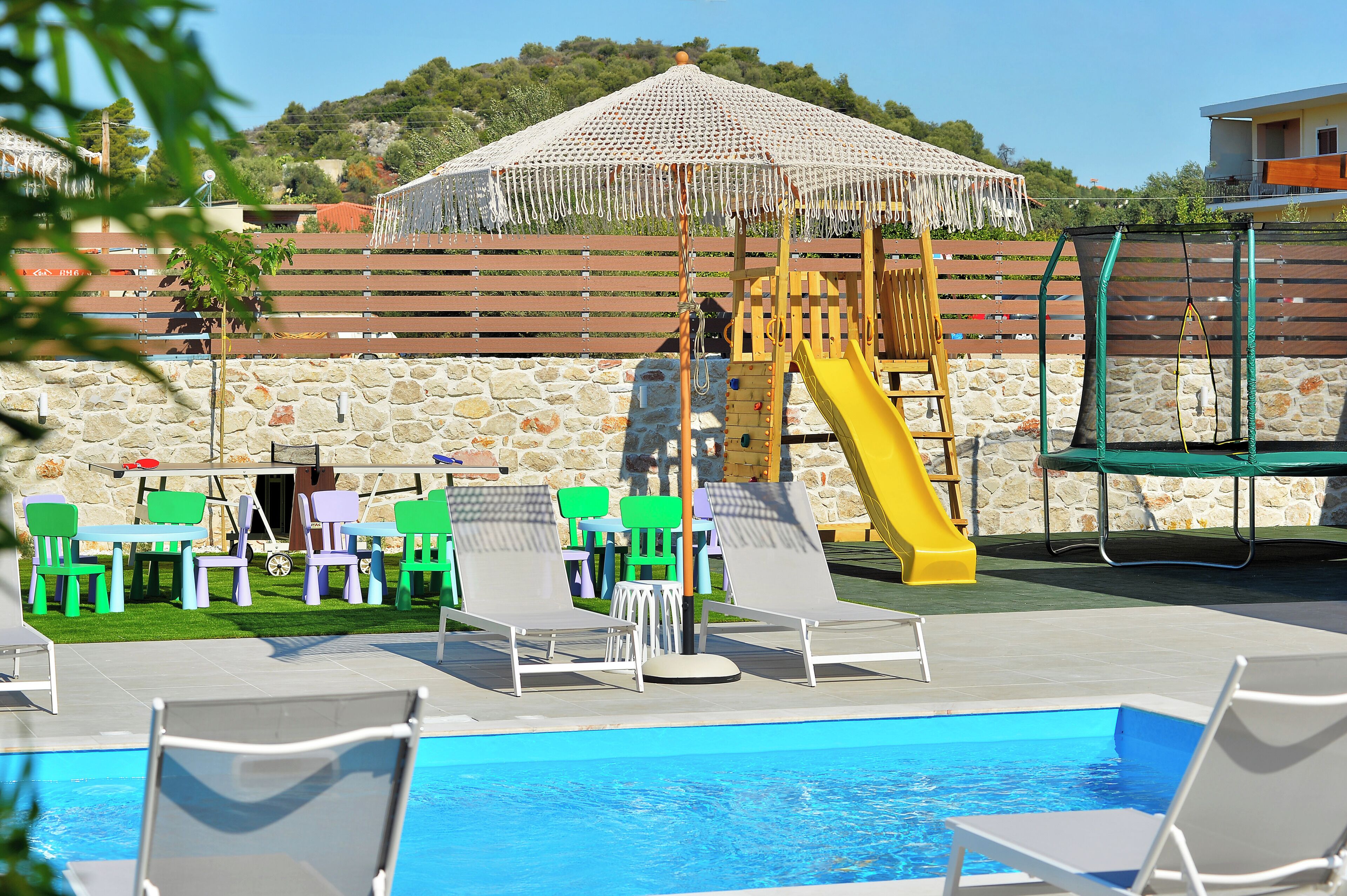 A pool area with lounge chairs, a slide, and a play structure.