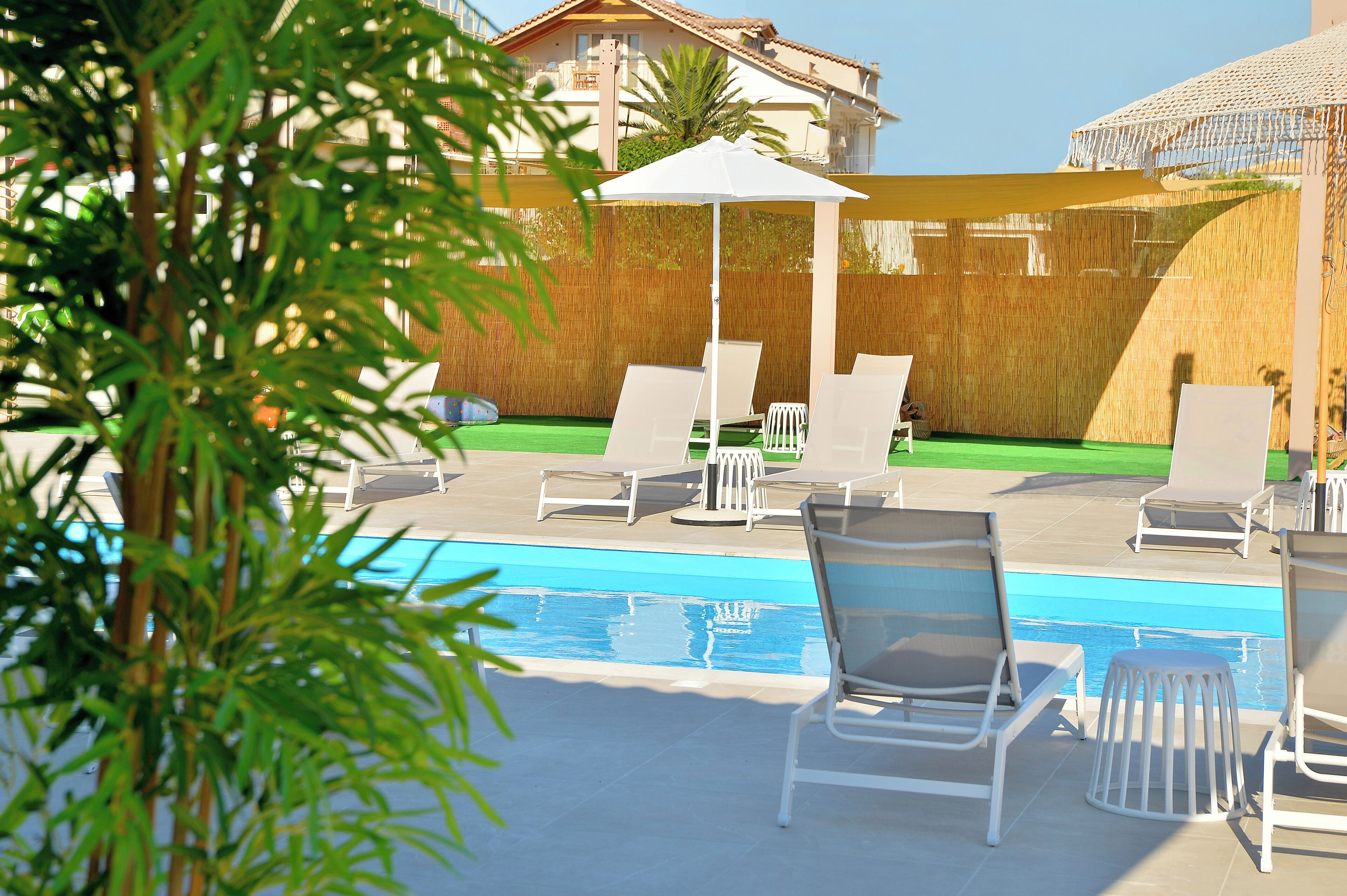 Ein Poolbereich mit weißen Liegestühlen und einem weißen Sonnenschirm.