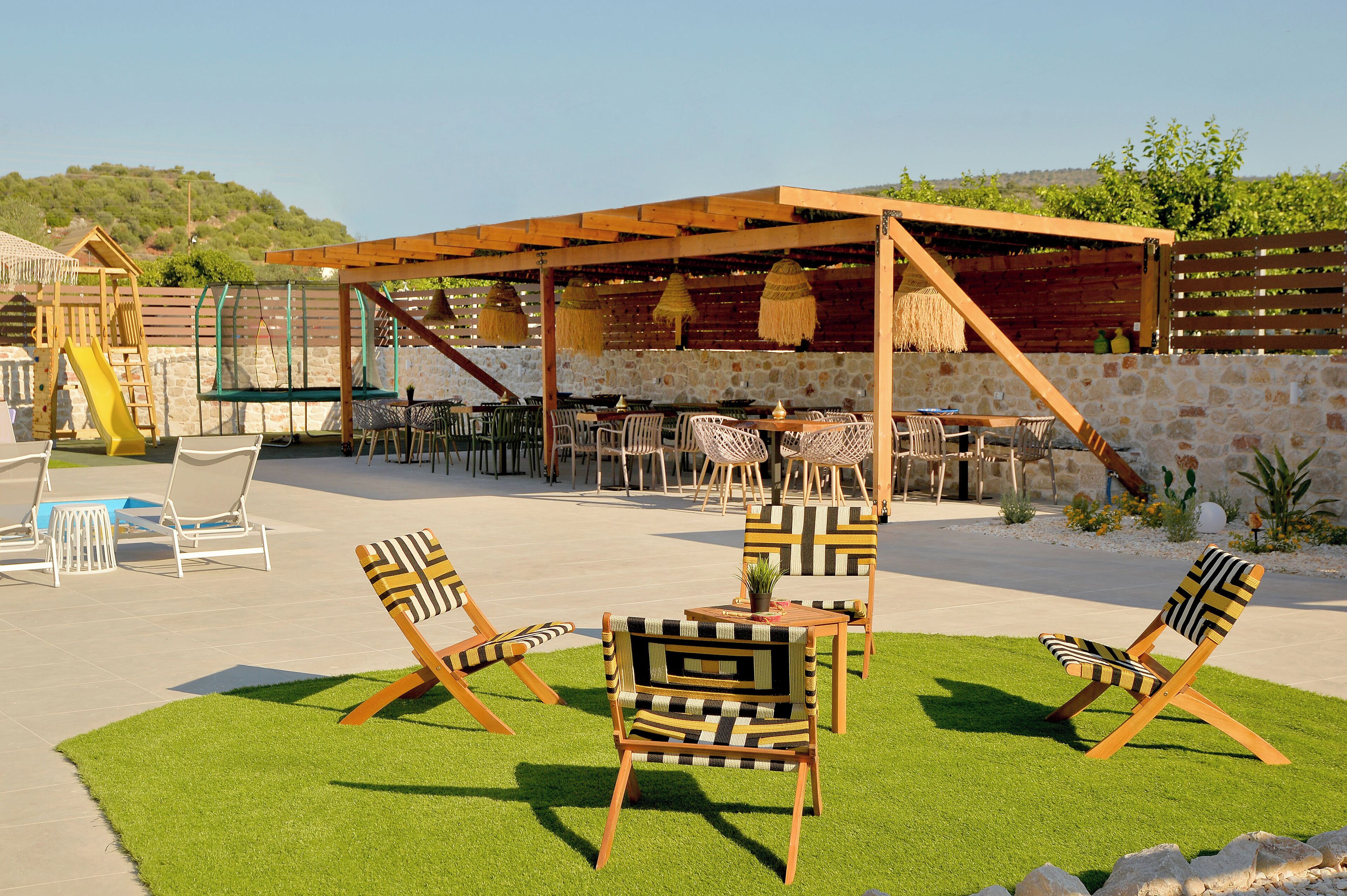 Un patio exterior con sillas de madera, una mesa y un columpio.