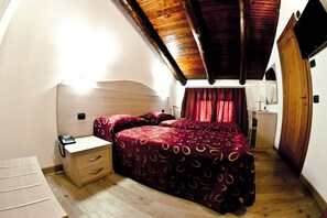 A bedroom with a wooden ceiling, a bed with a patterned bedspread, a bedside table with a phone, and a wardrobe.