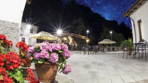 Une terrasse extérieure agrémentée de plantes en pot, de meubles pour s’asseoir et offrant une vue sur un ciel étoilé.