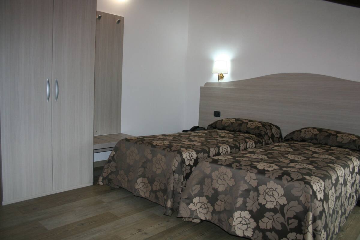 Een slaapkamer met een bed, nachtkastje, lamp en kledingkast.