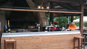 Un comptoir en bois équipé d’un grill, de tabourets et d’une variété de bouteilles et de verres.