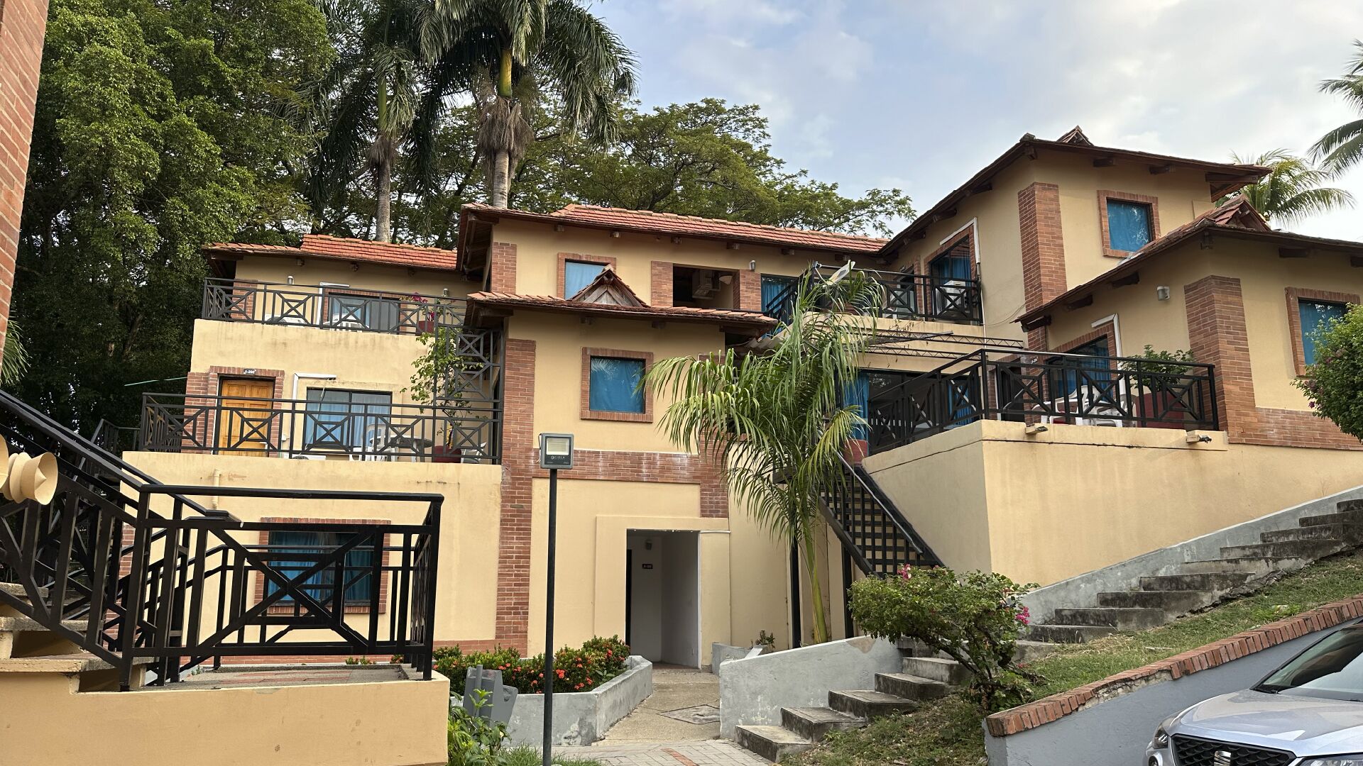 A multi-story residential building with a central entrance, balconies, and a staircase leading to the upper floors.