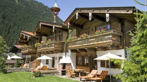 A chalet with wooden balconies, outdoor seating, and a stone fireplace. - BRUGGER - ChaletDorf (Mayrhofen)