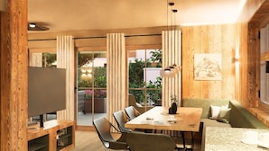 A modern living room with a wooden floor, a dining table, and a sofa. There is a TV on a wooden stand, and a window with curtains. - BRUGGER - ChaletDorf (Mayrhofen)