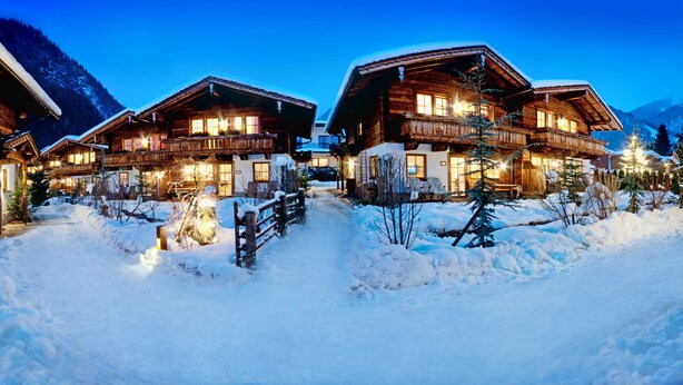 A wooden chalet-style hotel with multiple balconies and large windows, surrounded by snow-covered ground and trees. - BRUGGER - ChaletDorf (Mayrhofen)