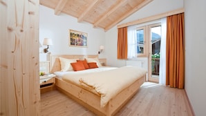 A wooden-framed bedroom with a bed, nightstands, and a window with curtains. - BRUGGER - ChaletDorf (Mayrhofen)