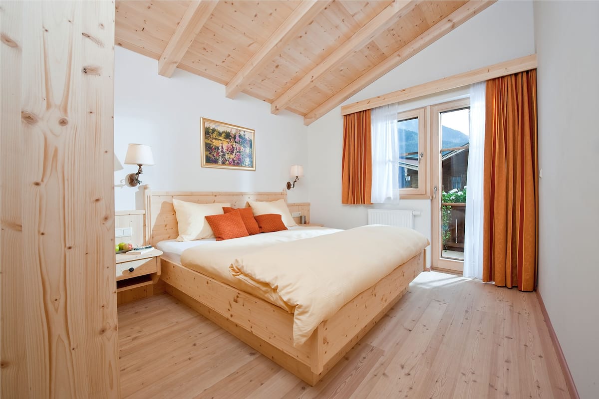 A wooden-framed bedroom with a bed, nightstands, and a window with curtains.