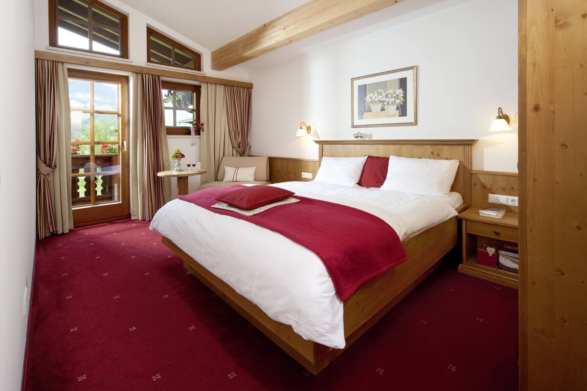 A well-lit bedroom with a large bed, wooden headboard, and two bedside tables with lamps.