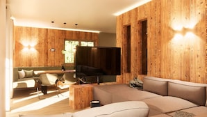 A modern living room with a large flat-screen TV, wooden panel walls, a sofa, a coffee table, and a dining area with chairs. - BRUGGER - ChaletDorf (Mayrhofen)