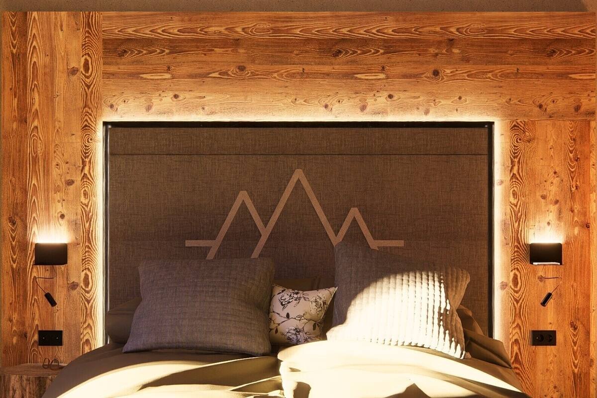 A bed with a wooden headboard, two pillows, and a geometric design on the headboard.