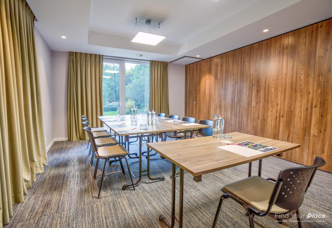 A conference room with a long table, chairs, and a wooden panel wall.