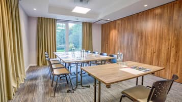 Une salle de conférence avec une longue table, des chaises et un mur recouvert de panneaux en bois.