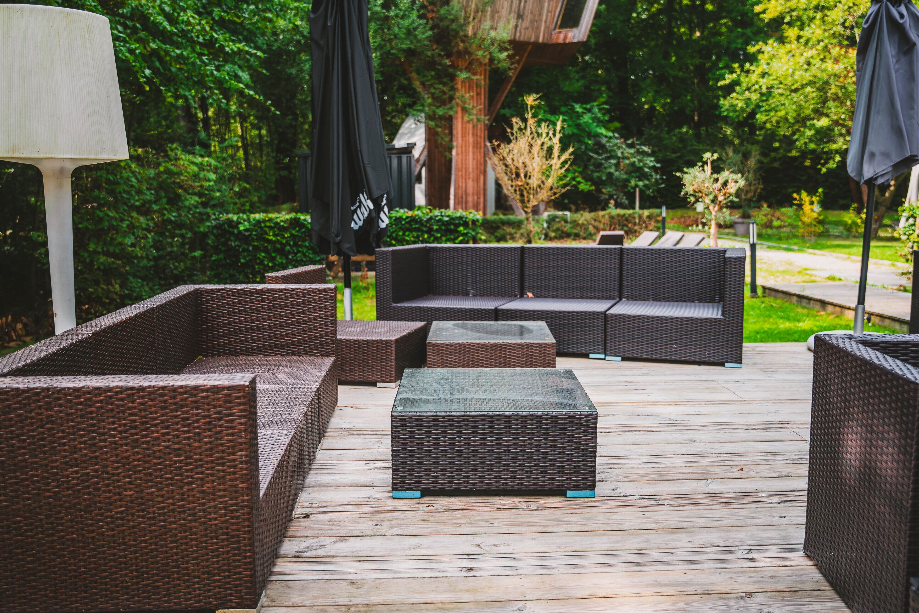Una terraza de madera con muebles de mimbre, incluyendo sofás y una mesita de centro.