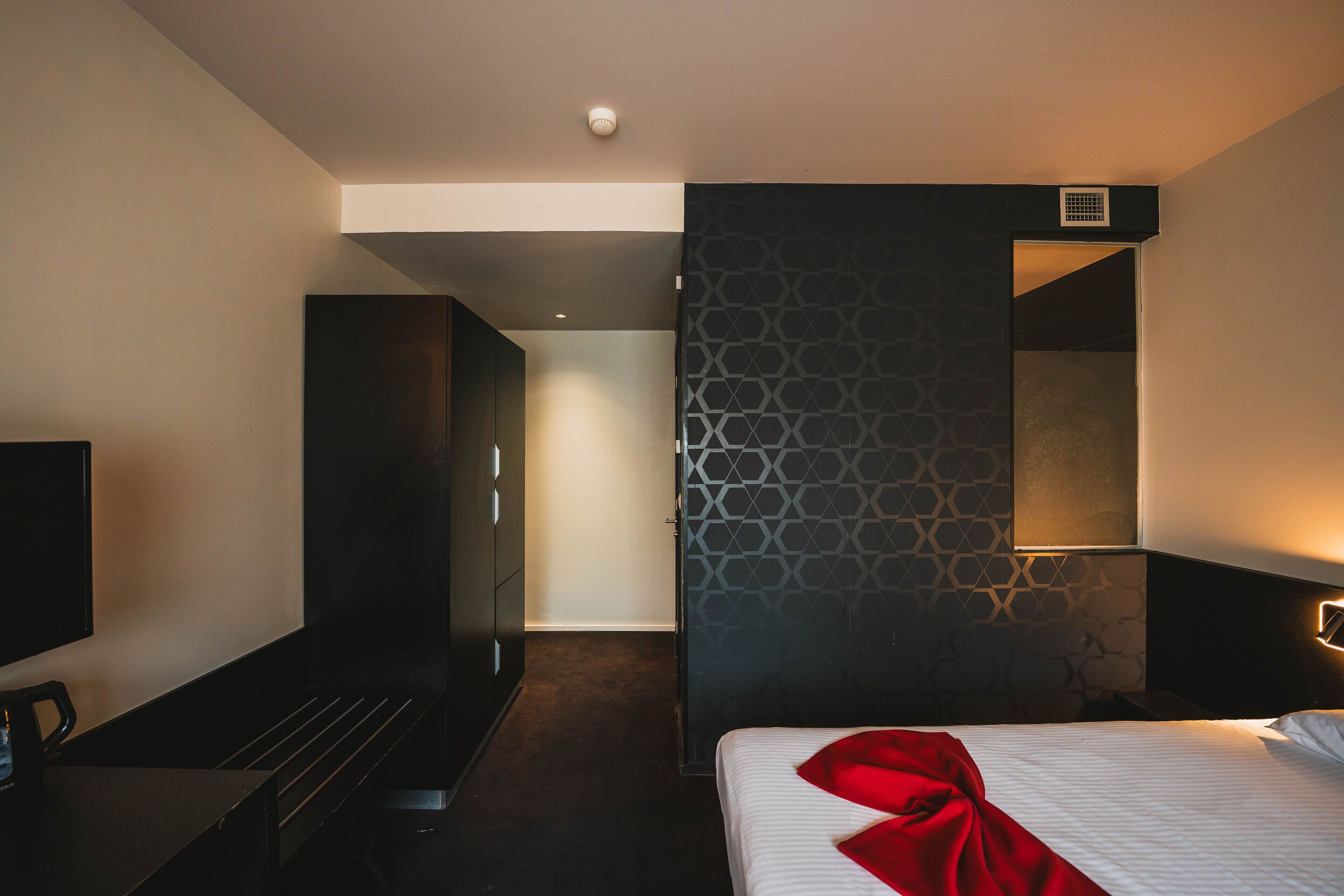 Une chambre d’hôtel moderne équipée d’un lit, d’une télévision, d’un bureau et d’une armoire.
