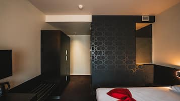 Une chambre d’hôtel moderne équipée d’un lit, d’une télévision, d’un bureau et d’une armoire.