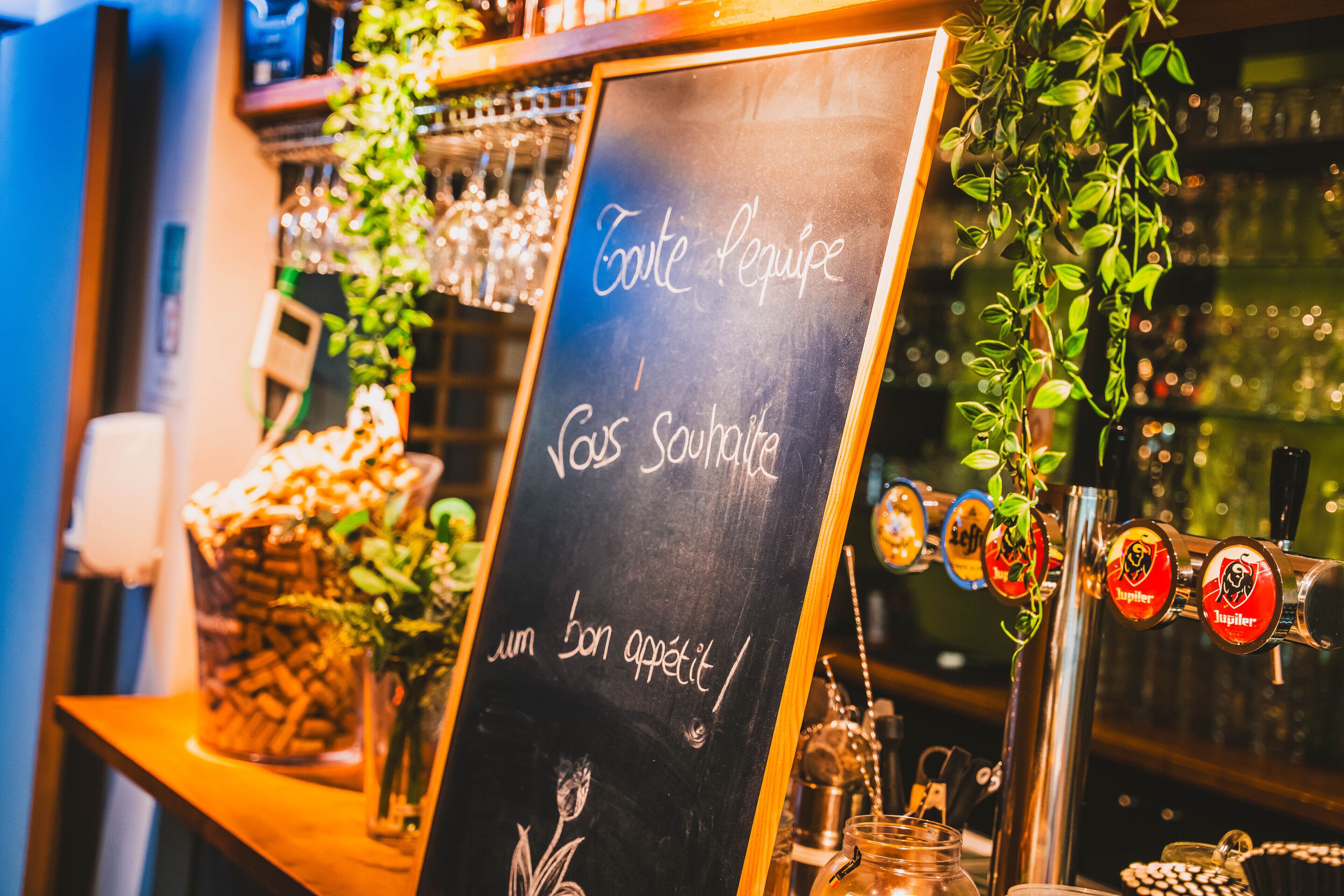 Eine Bar mit einer Kreidetafel, die die Menüpunkte 'Toiture Requipe' und 'Vos Souffles' auflistet.