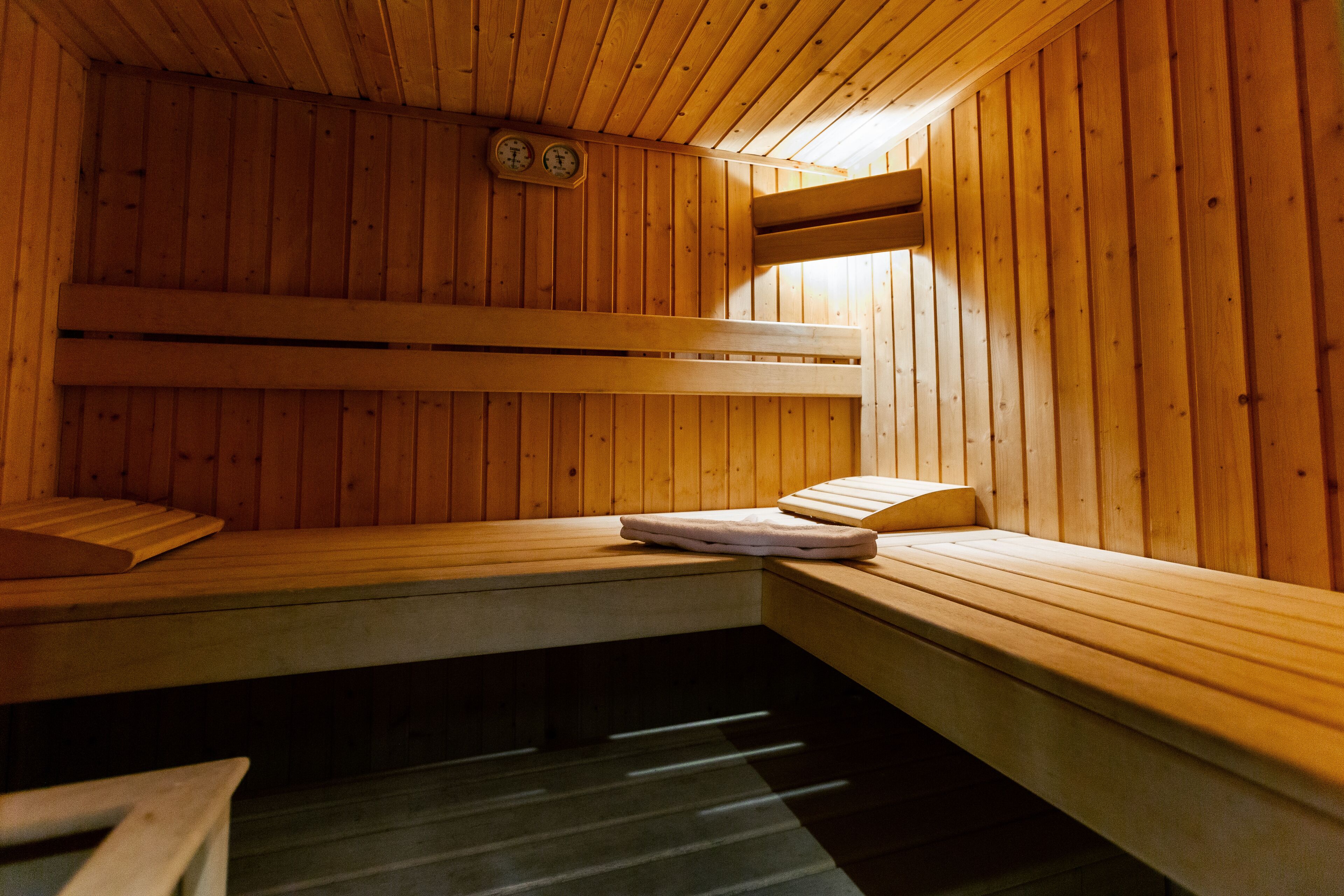 Una sauna con bancos de madera y un reloj visible en la pared.