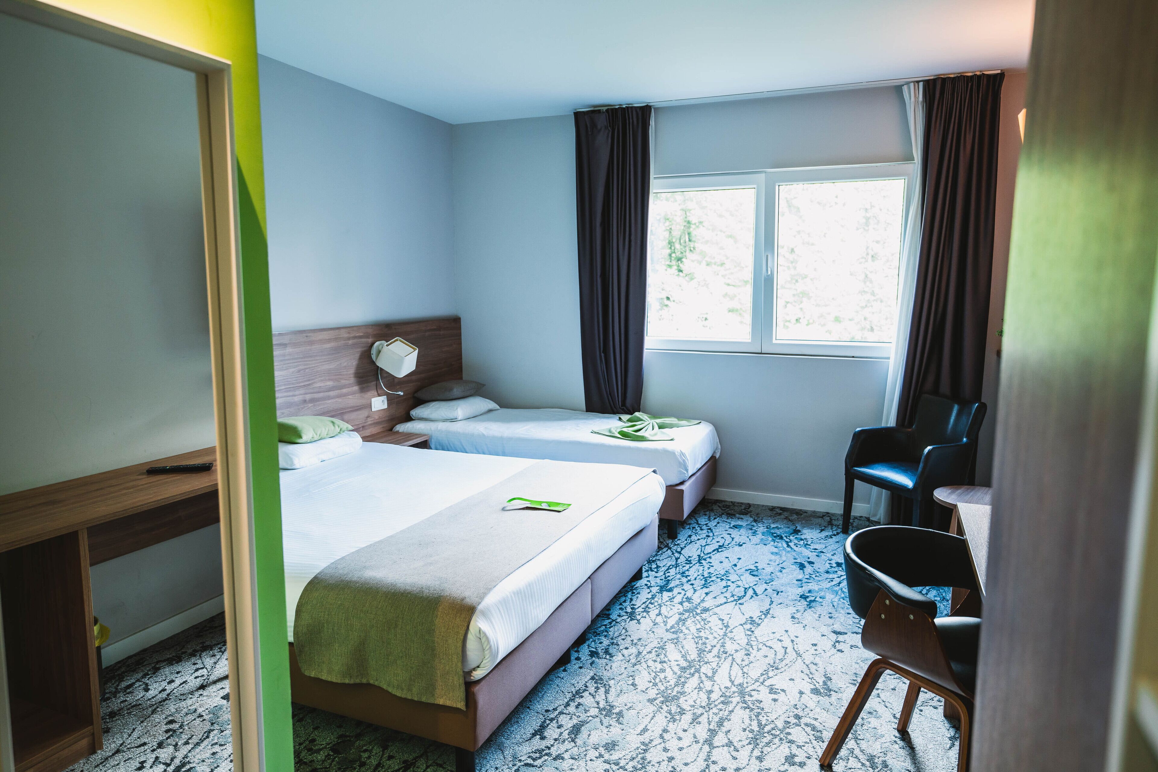 A hotel room with two beds, a desk, and a chair.