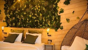 Un dormitorio acogedor con una cama, una silla colgante y una mesita.