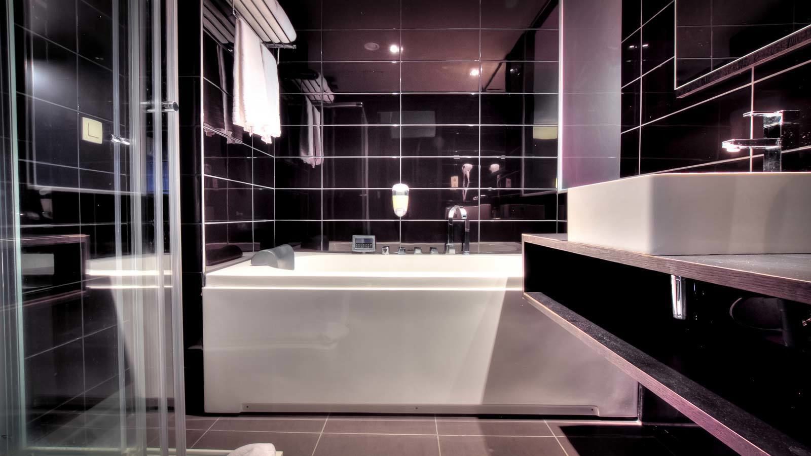 A modern bathroom with a large bathtub, a separate shower area, and a vanity with a mirror.