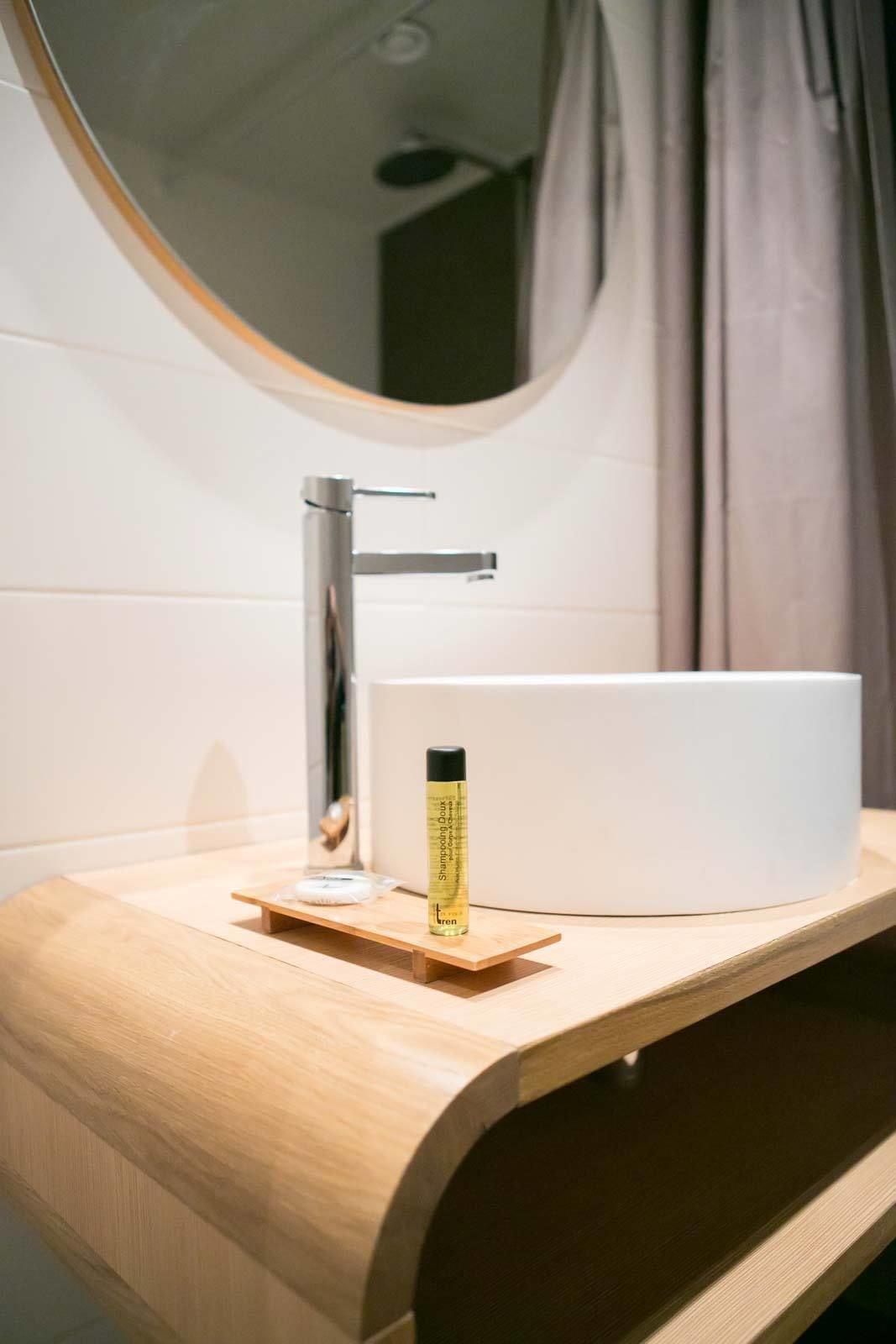 A modern bathroom with a round mirror, a chrome faucet, and a white vessel sink.
