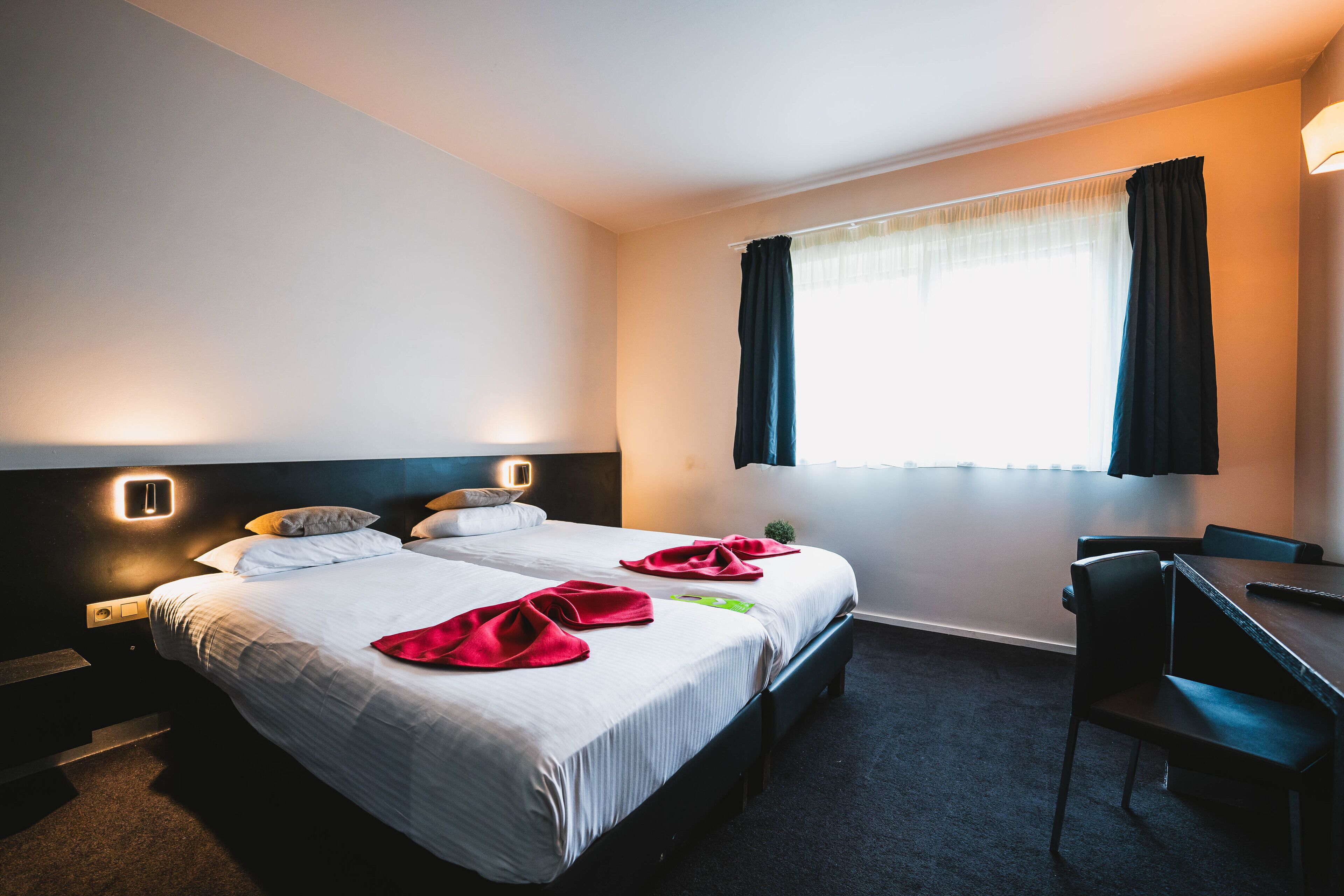 Een hotelkamer met twee bedden, een bureau en een stoel.