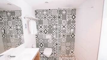 Une salle de bain avec un lavabo blanc, des toilettes et un espace douche agrémenté de carreaux à motifs.