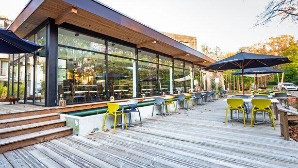 Un área de comedor al aire libre con muebles modernos y ventanas grandes.