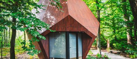 Una cabaña de madera moderna y hexagonal en un bosque.